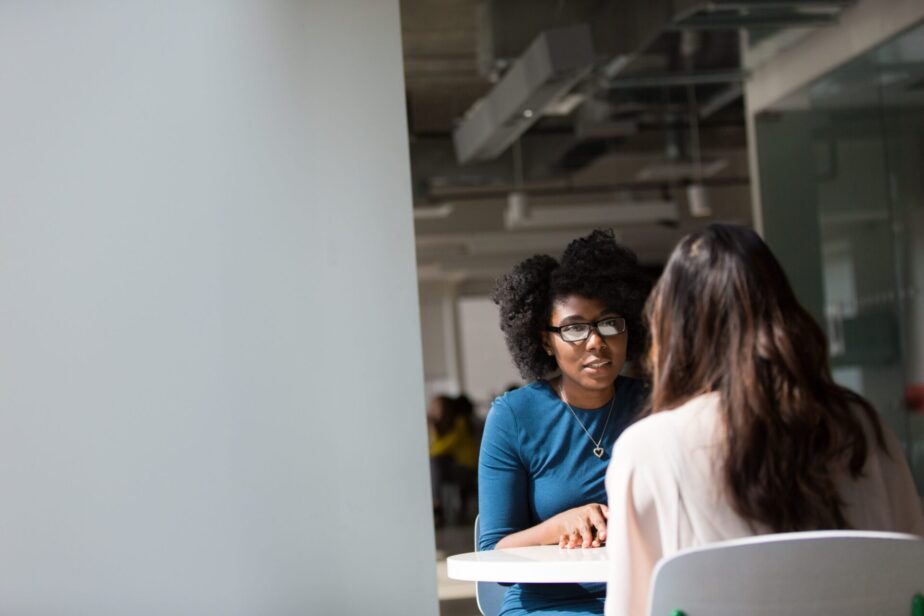 A picture of a woman interviewing another woman at a job interview. Learn what questions to ask at the end of an interview.