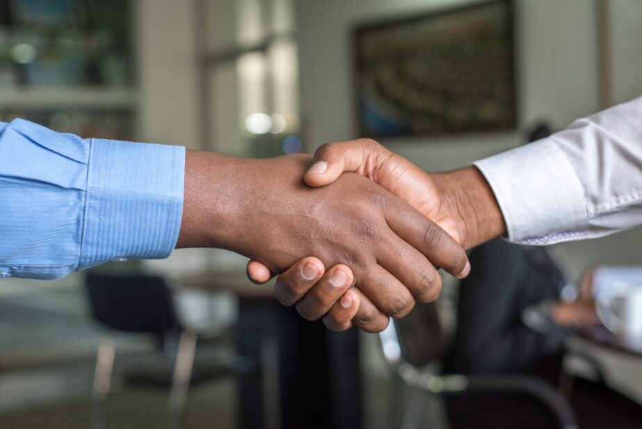 A picture of a man shaking another man's hand at a job interview. Learn what questions to ask at the end of an interview.