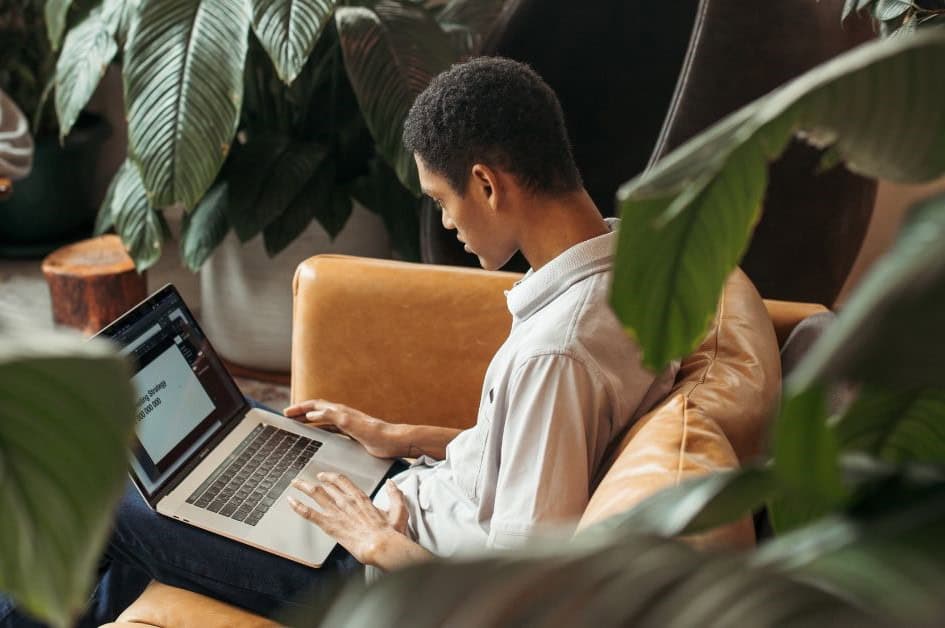 An image of an Application Security Engineer sitting on a sofa and working.