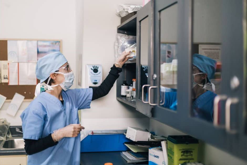 An image of a Physician Assistant at work, reaching into a medicine cupboard.