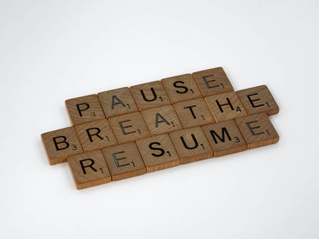 Image which says, "Pause, Breath, Resume" with each letter written on individual wooden blocks.