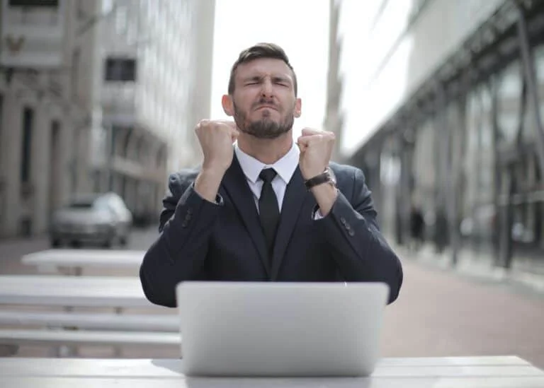 A Man Celebrates Success After Securing A Job After Using An Ai Interview Coach. The Man Is Wearing A Suit And Sitting In Front Of A Computer.